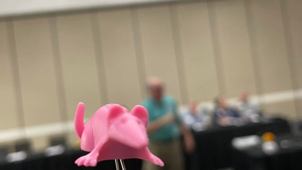 A pink toy lizard is in front of some people.