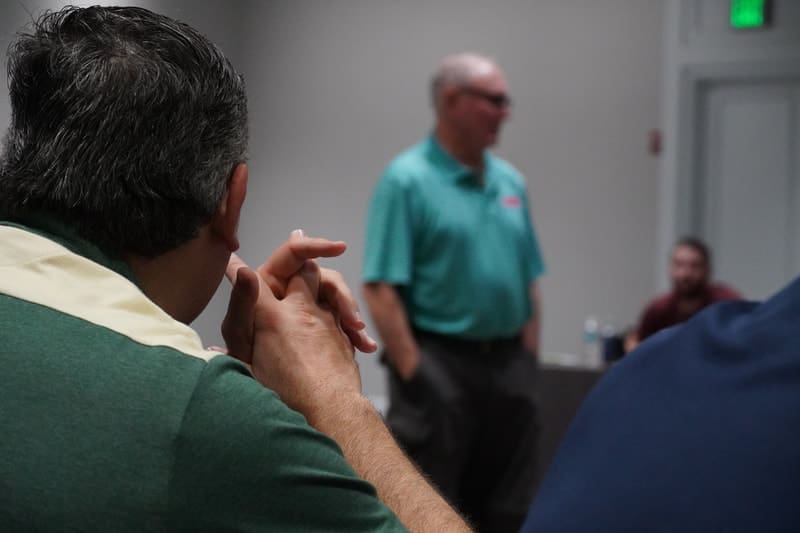 A group of people in a room with one man standing up.