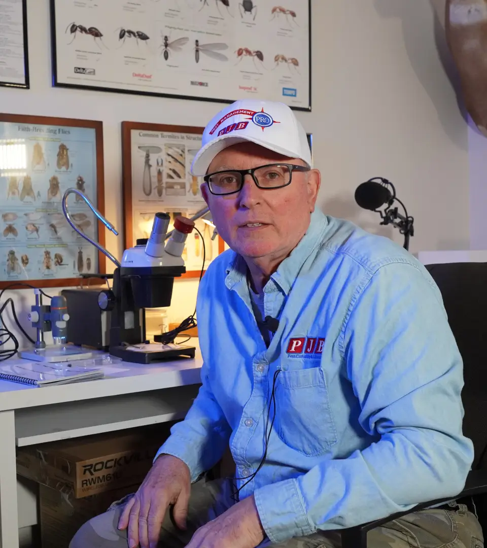 A man sitting at his desk wearing glasses and a hat.