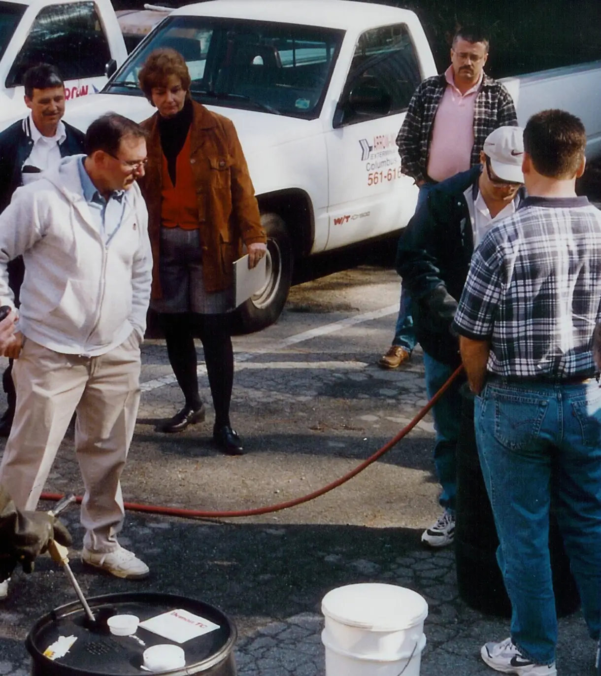 A group of people standing around a white bucket.