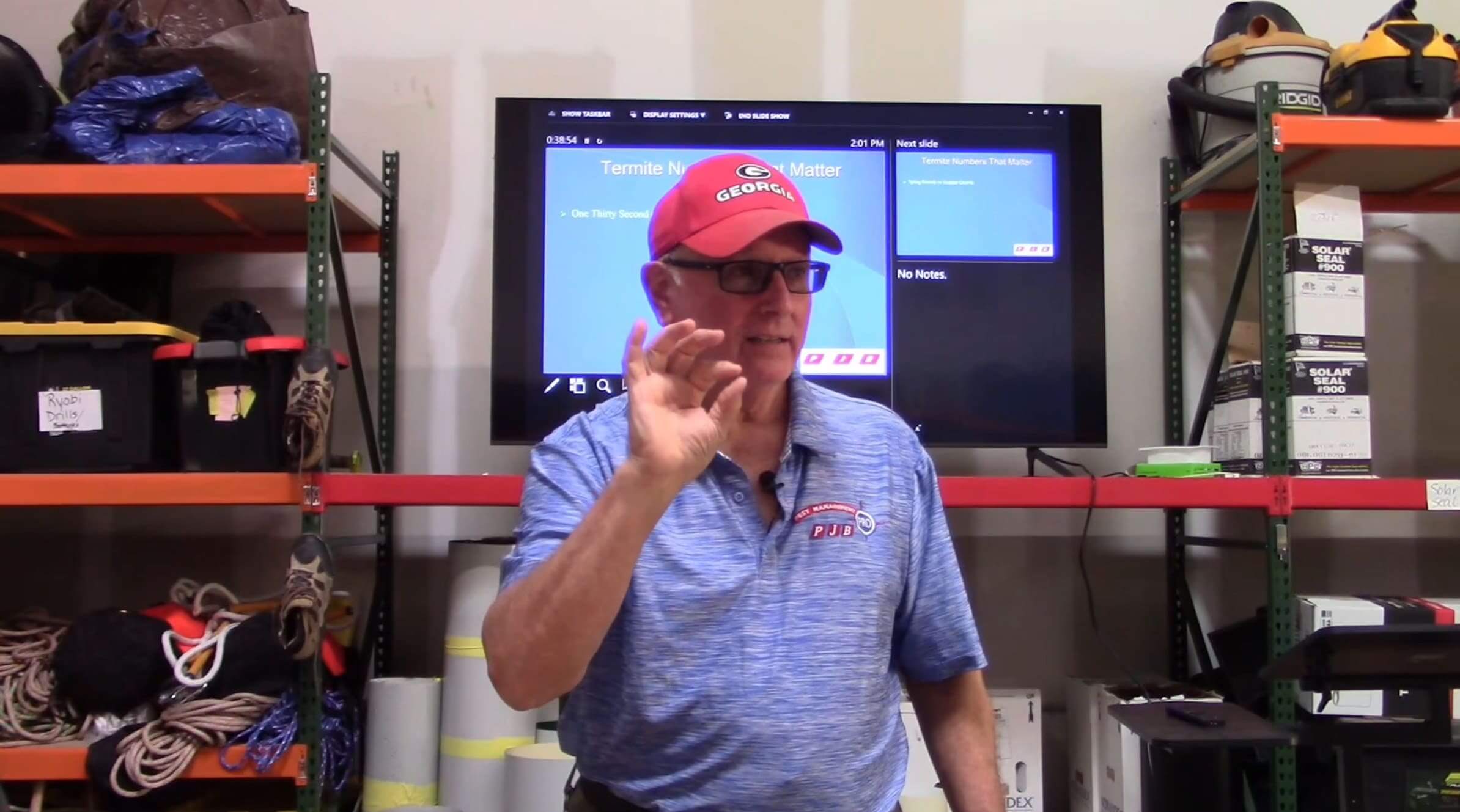 A man in blue shirt and red hat standing next to a tv.