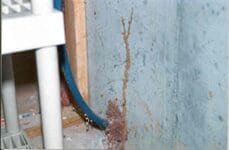 A pipe that is in the corner of a wall.