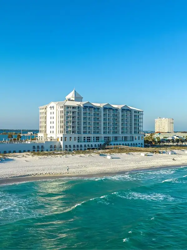 A large white building on the beach near water.