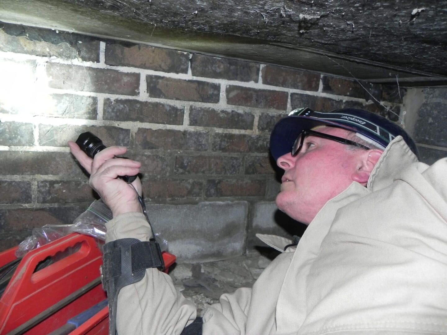 Person inspecting brick wall with flashlight.