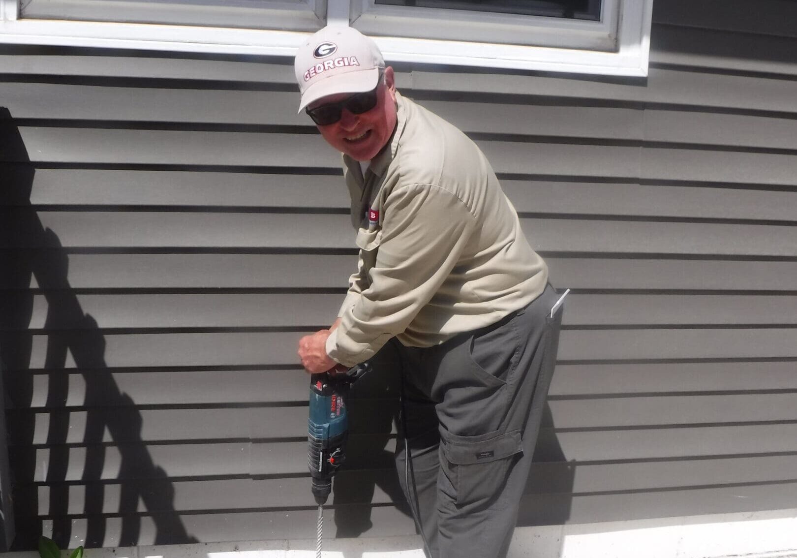 Man drilling near a house window.