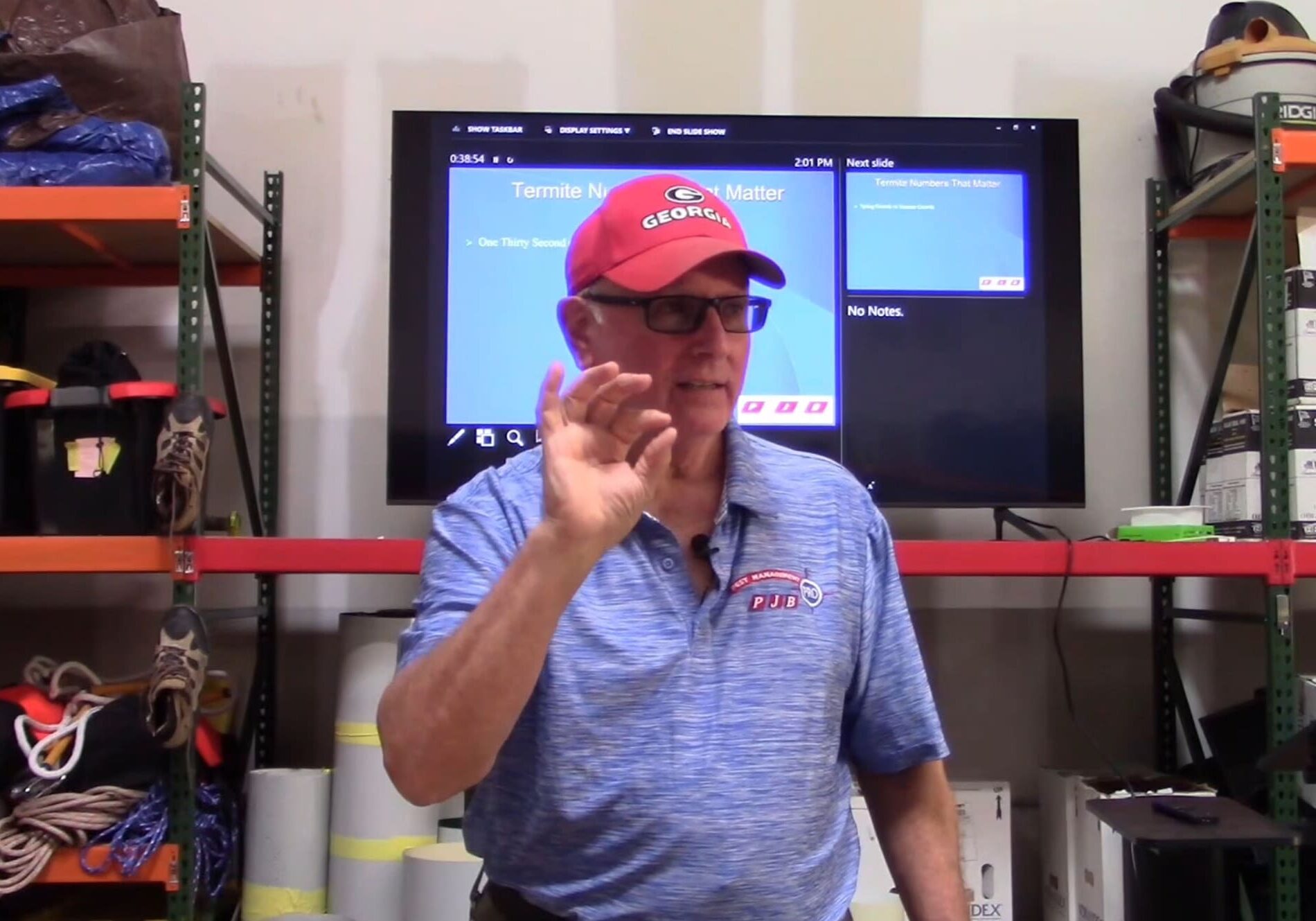 A man in blue shirt and red hat standing next to a tv.