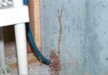 A pipe that is in the corner of a wall.